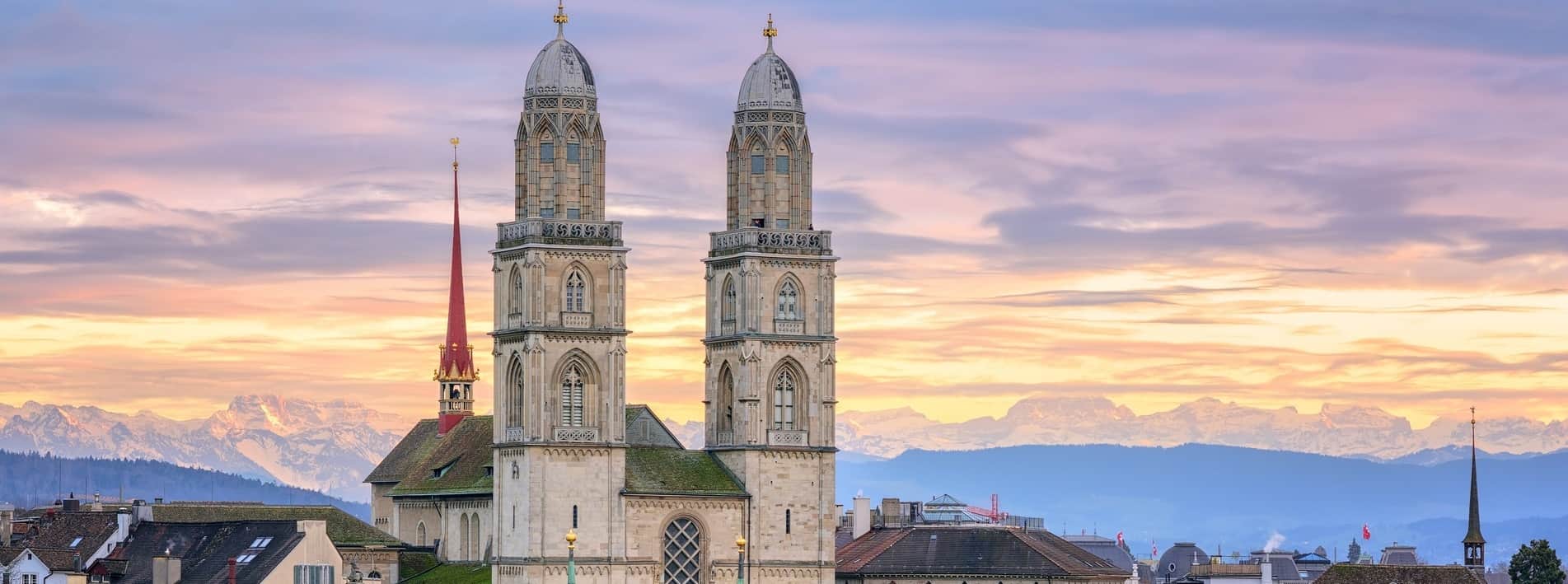 Zurich city center with snow covered Alps mountains in backgroun Zurich city center and cathedral towers with snow covered Alps mountains in background on sunset, Switzerland